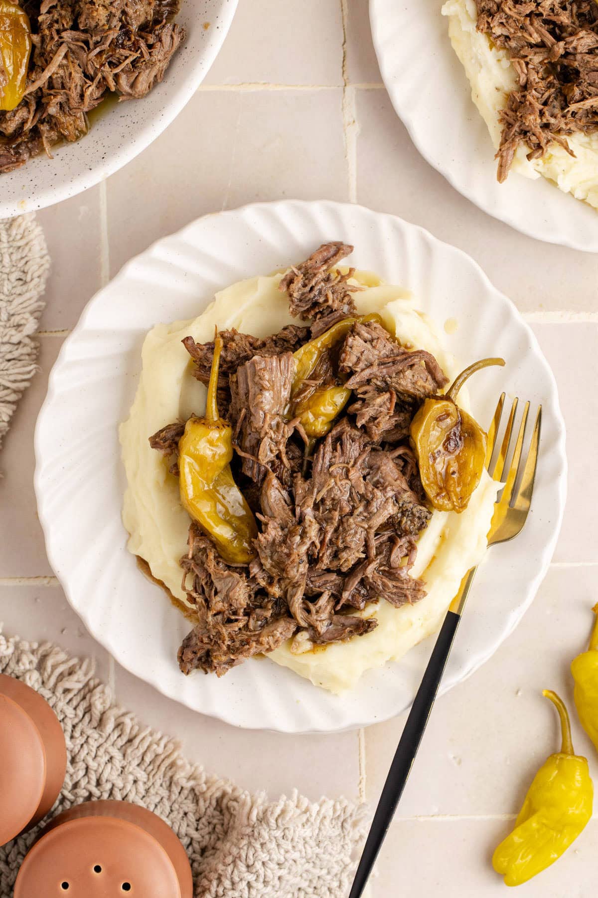 Mississippi Pot Roast shredded on top of mashed potatoes and peperoncino peppers