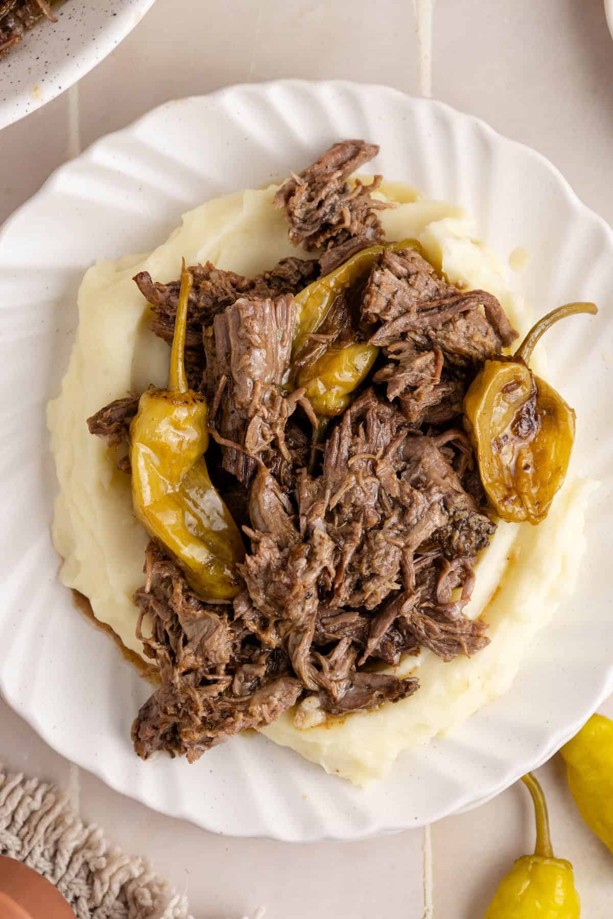 Mississippi Pot Roast close up over a bed of mashed potatoes and peperoncinis