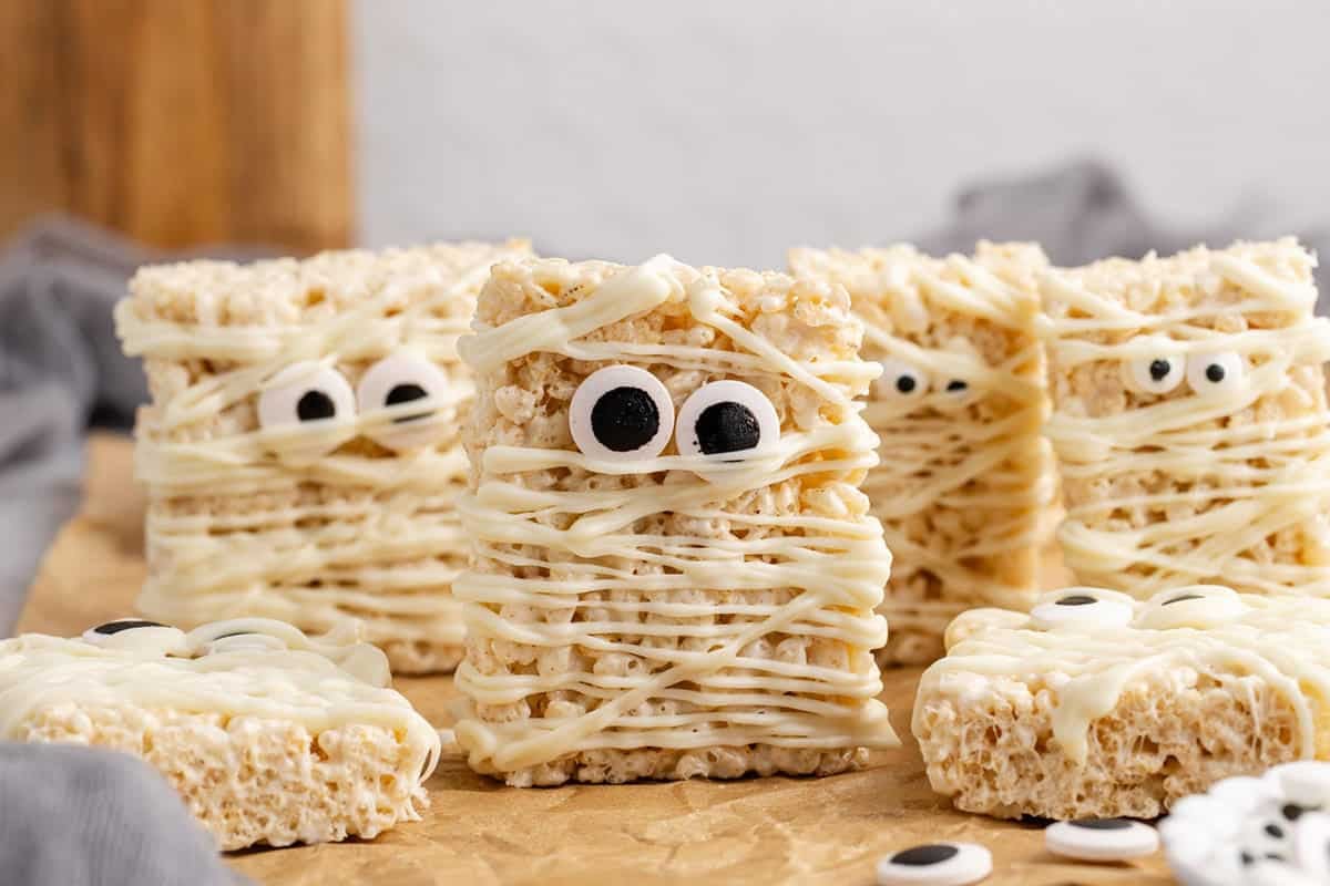 Mummy Rice Krispie Treats on parchment paper with some standing up and some laying down