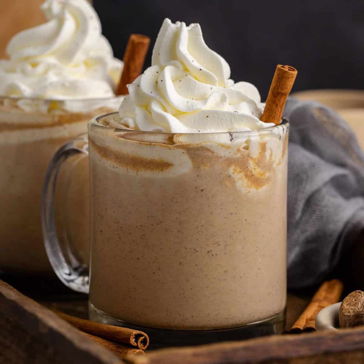 Pumpkin Chai Lattes in a tray with whipped cream and cinnamon sticks