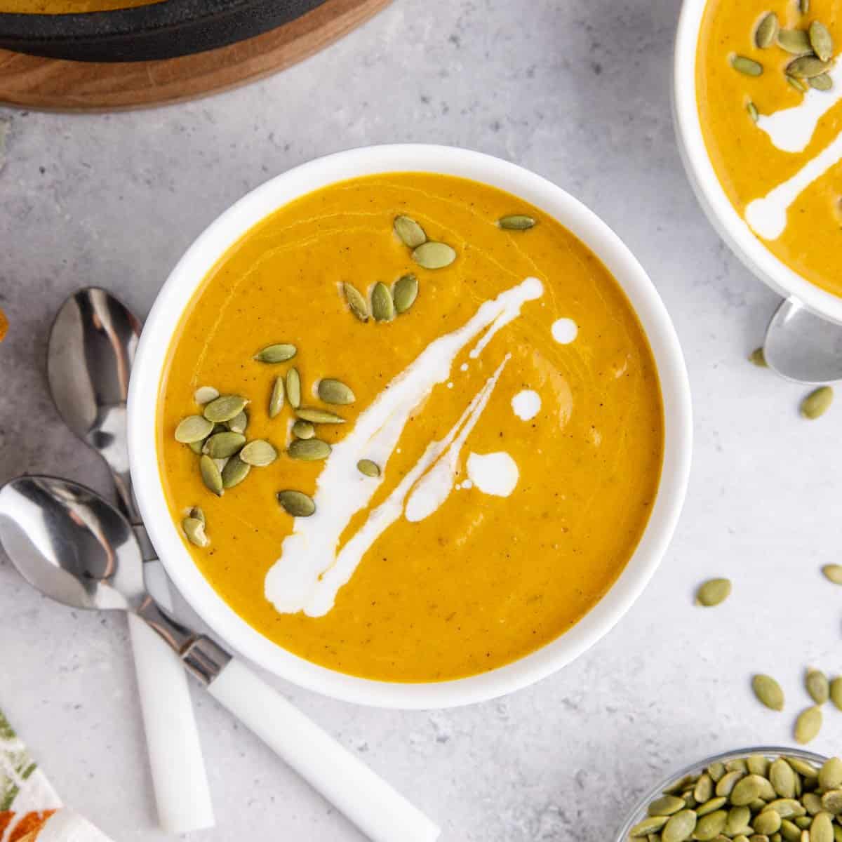 Pumpkin Carrot Soup in bowls with pumpkin seeds garnishing
