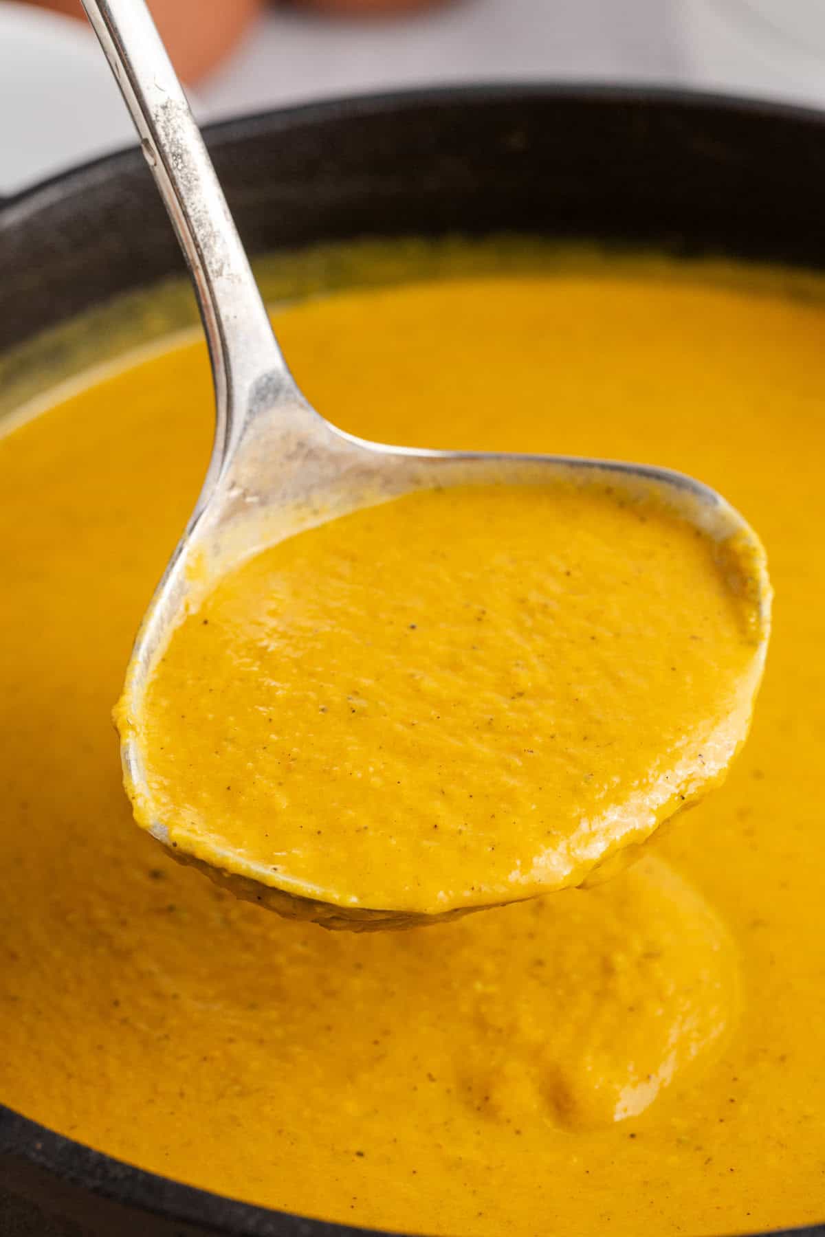 Pumpkin Carrot Soup on a ladle over the soup pot