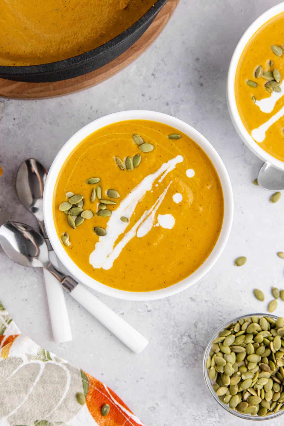 Pumpkin Carrot Soup from overhead in a bowl with pumpkin seeds and drizzle coconut milk