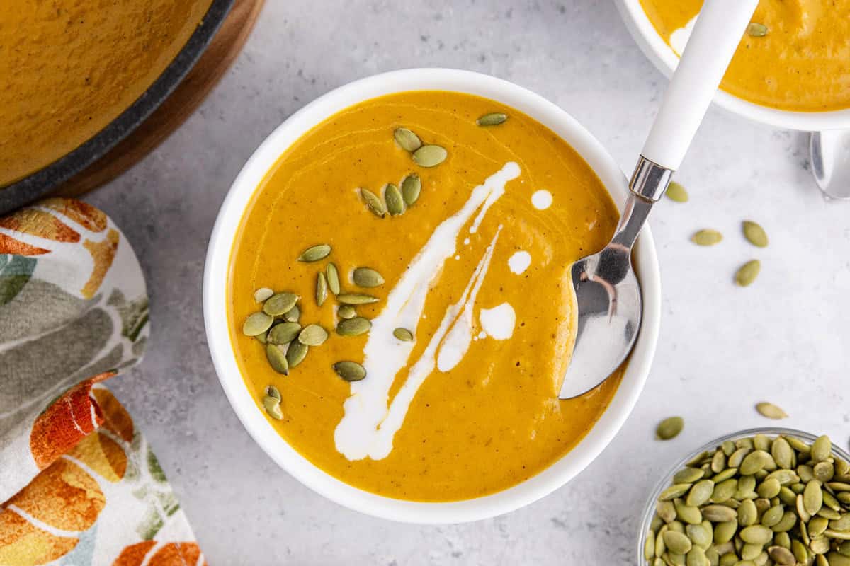 Pumpkin Carrot Soup from overhead in a bowl with pumpkin seeds and drizzle coconut milk
