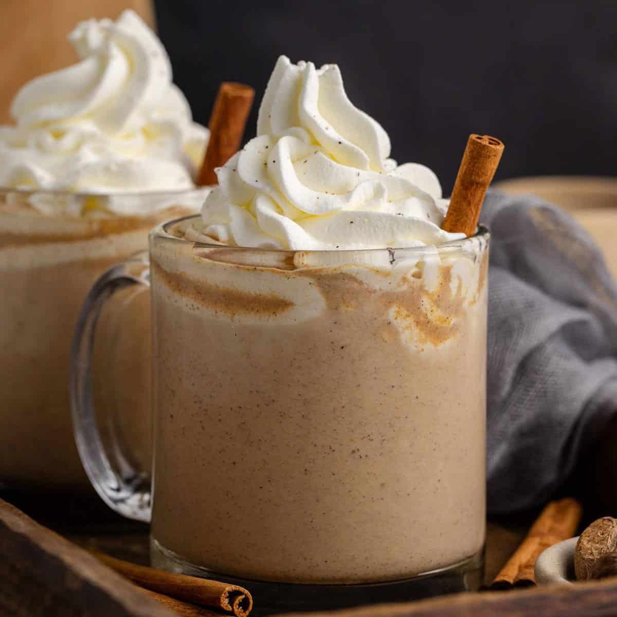 Pumpkin Chai Latte in glass mugs with a cinnamon stick and whipped cream