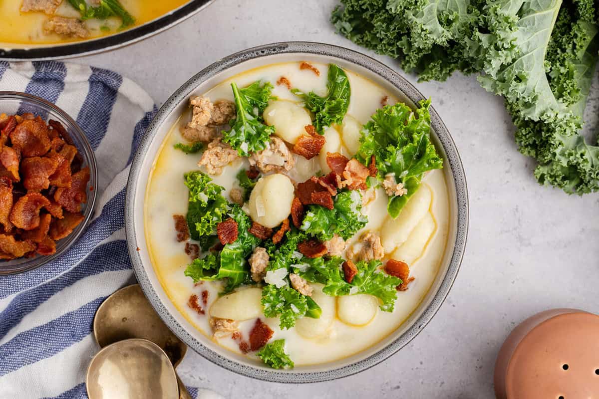 Zuppa Toscana overhead image in a bowl with kale and bacon beside