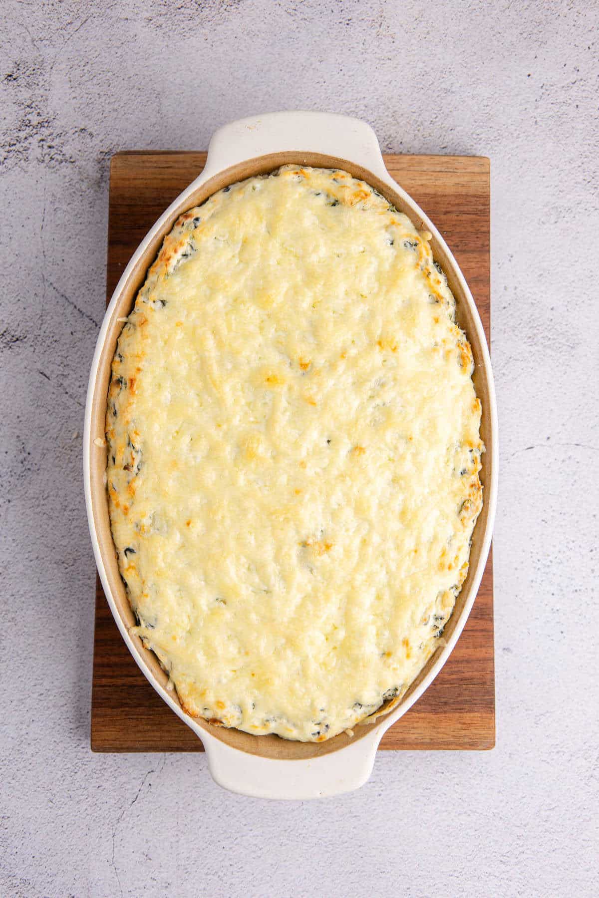Baked Spinach and Artichoke Dip in Oval Baking Dish with Golden Cheese Top Layer