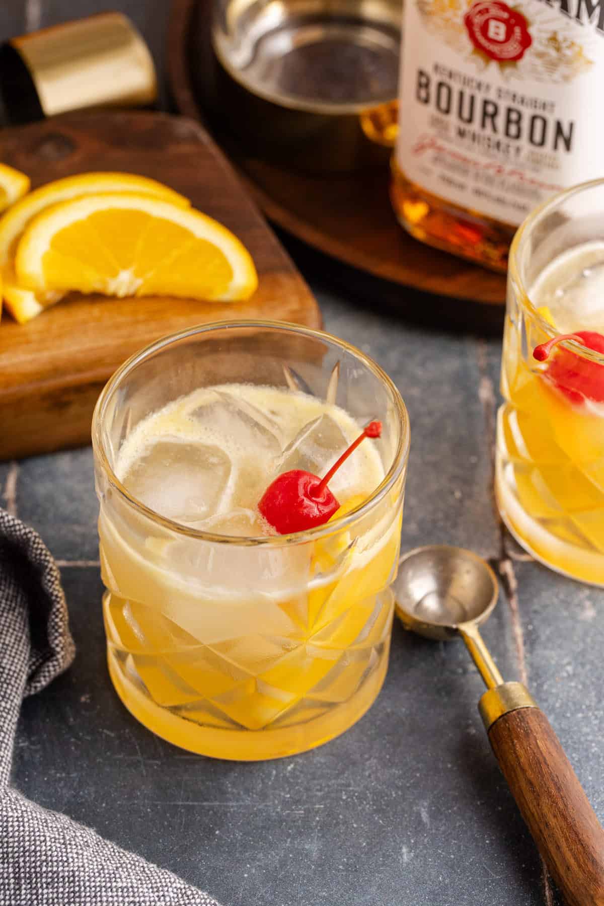 Bourbon Lemon Cocktail in a Glass Garnished with a Maraschino Cherry and Lemon Wedge