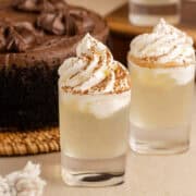 Chocolate Cake Shot in Shot Glasses and Garnished with Whipped Cream and Cocoa Powder with Chocolate Cake in Background