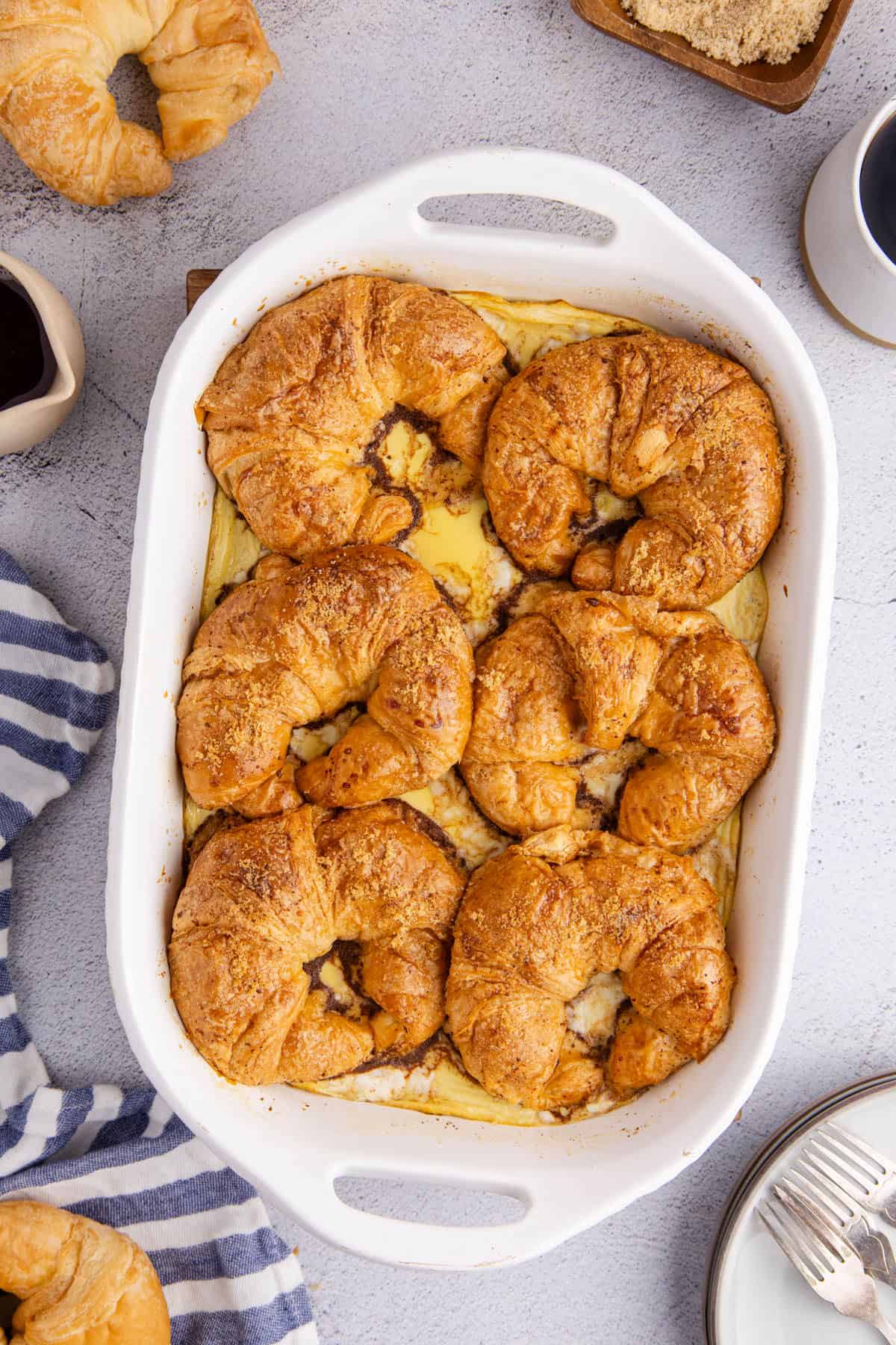 Croissant French Toast Casserole Overhead with Croissants and Maple Syrup Around