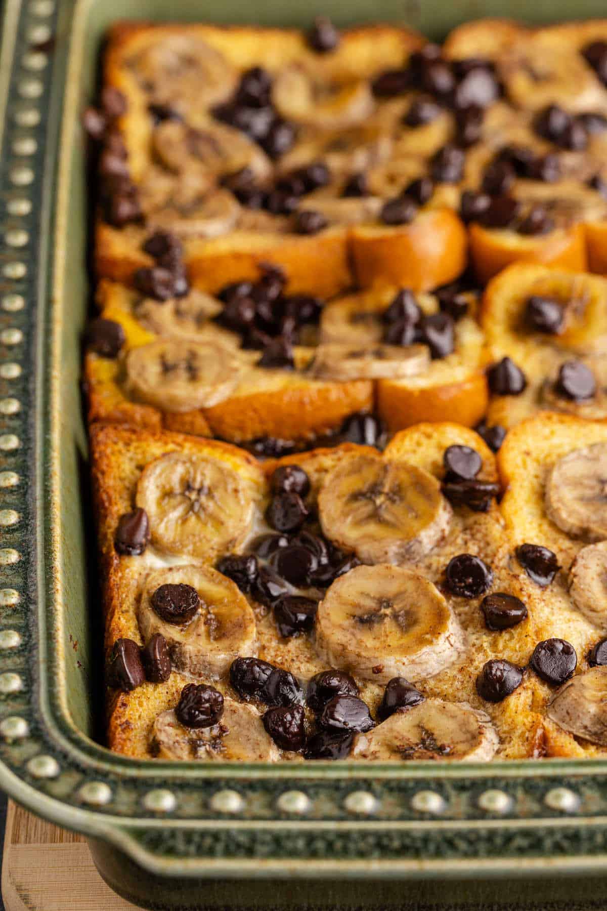 Banana French Toast Bake with Chocolate Chips and Sliced Banana on Top in Baking Dish