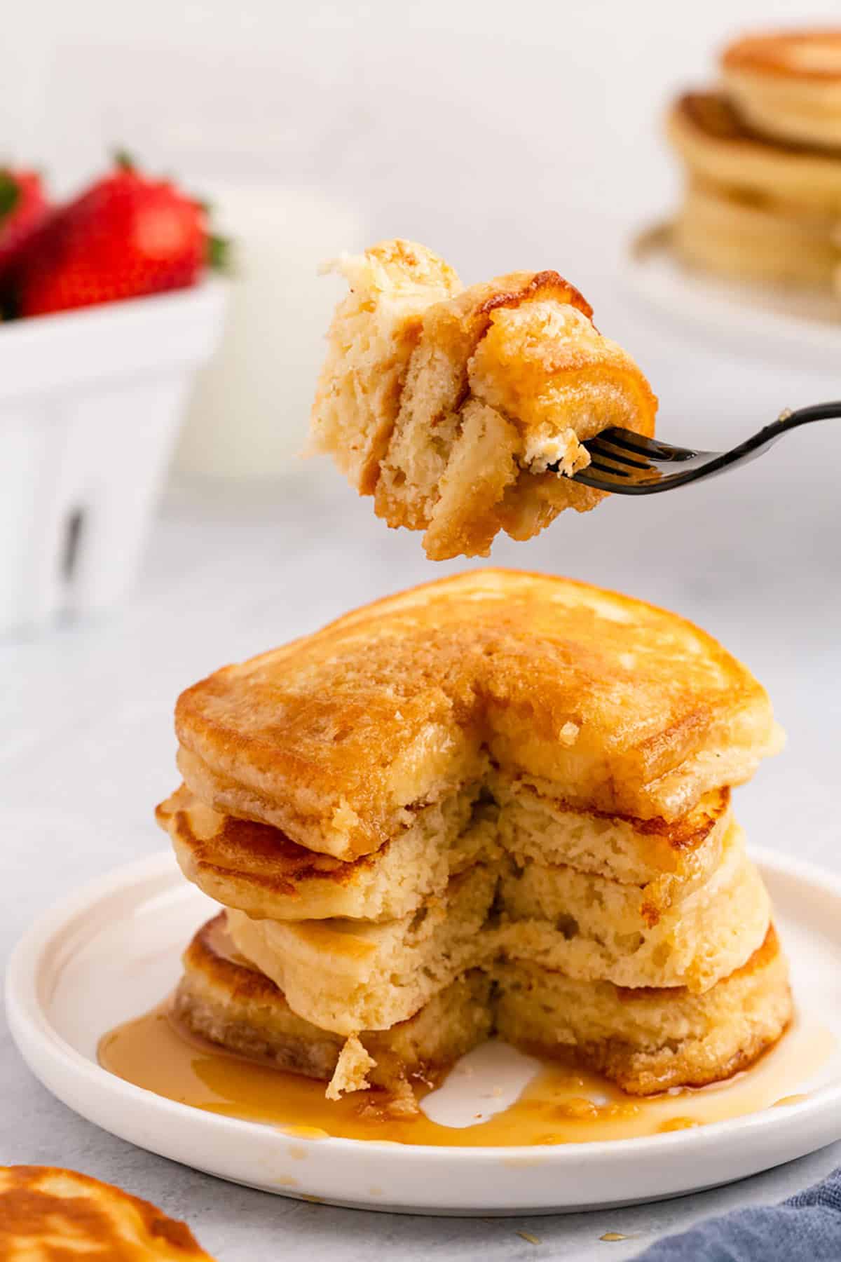 Crispy Fluffy Pancakes Stacked on a Plate with Forkful Showing the Inside Texture