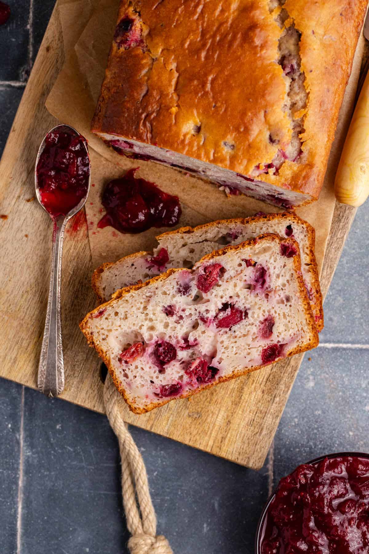 Cranberry Sauce Bread on a cutting board from above with a spoon of leftover sauce