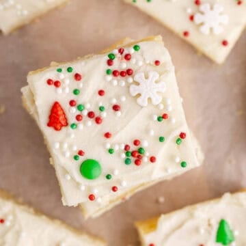 Frosted Sugar Cookie Bars decorated for Christmas on parchment paper