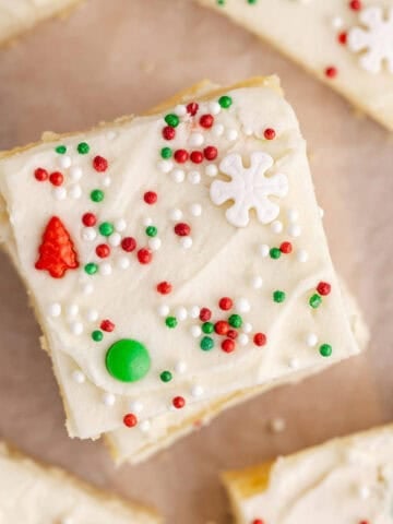 Frosted Sugar Cookie Bars decorated for Christmas on parchment paper