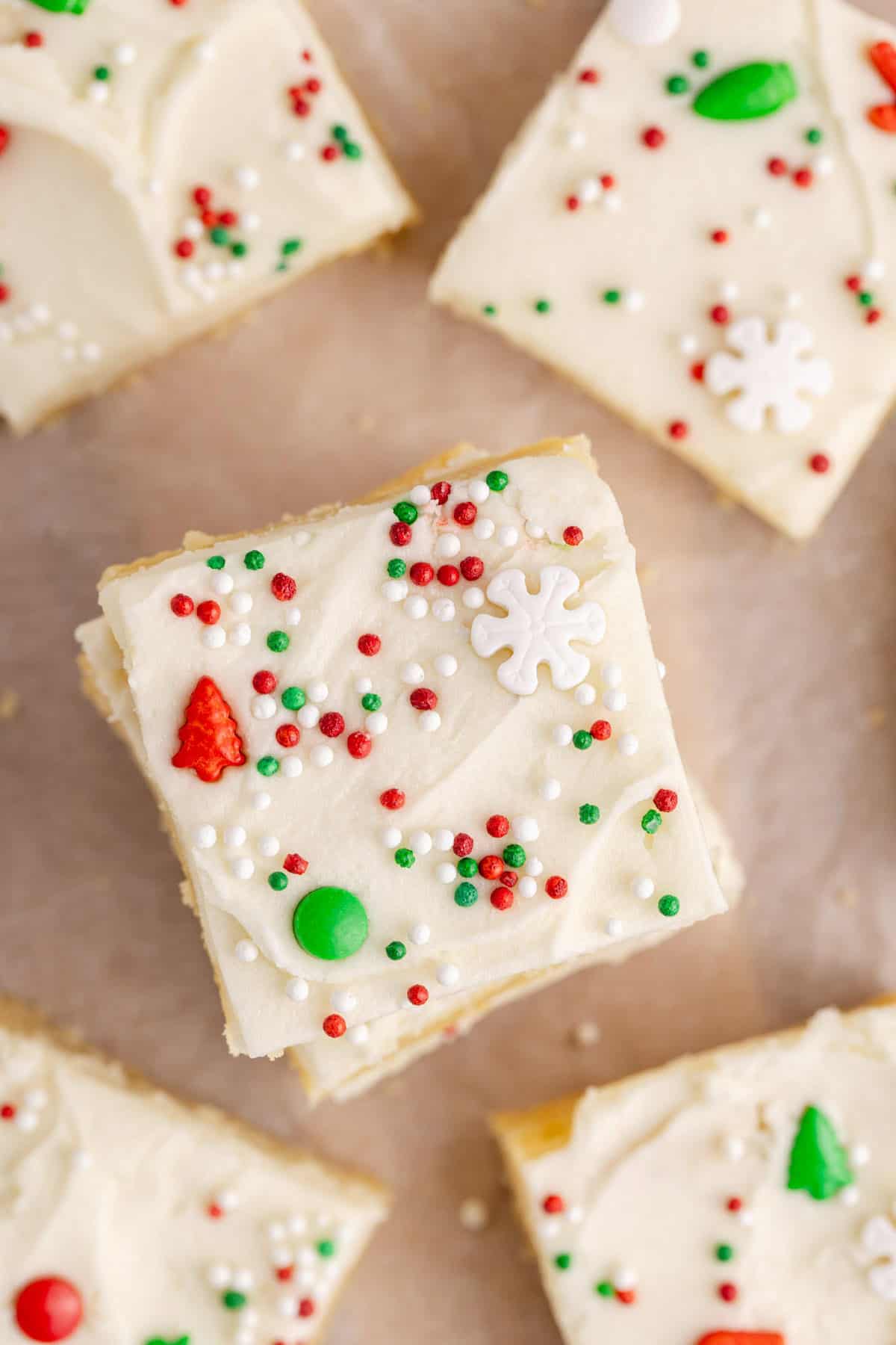 Frosted Sugar Cookie Bars on parchment paper decorated for Christmas