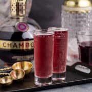 Grape Ape Shots in Tall Shot Glasses on a Tray with Chambord in Background