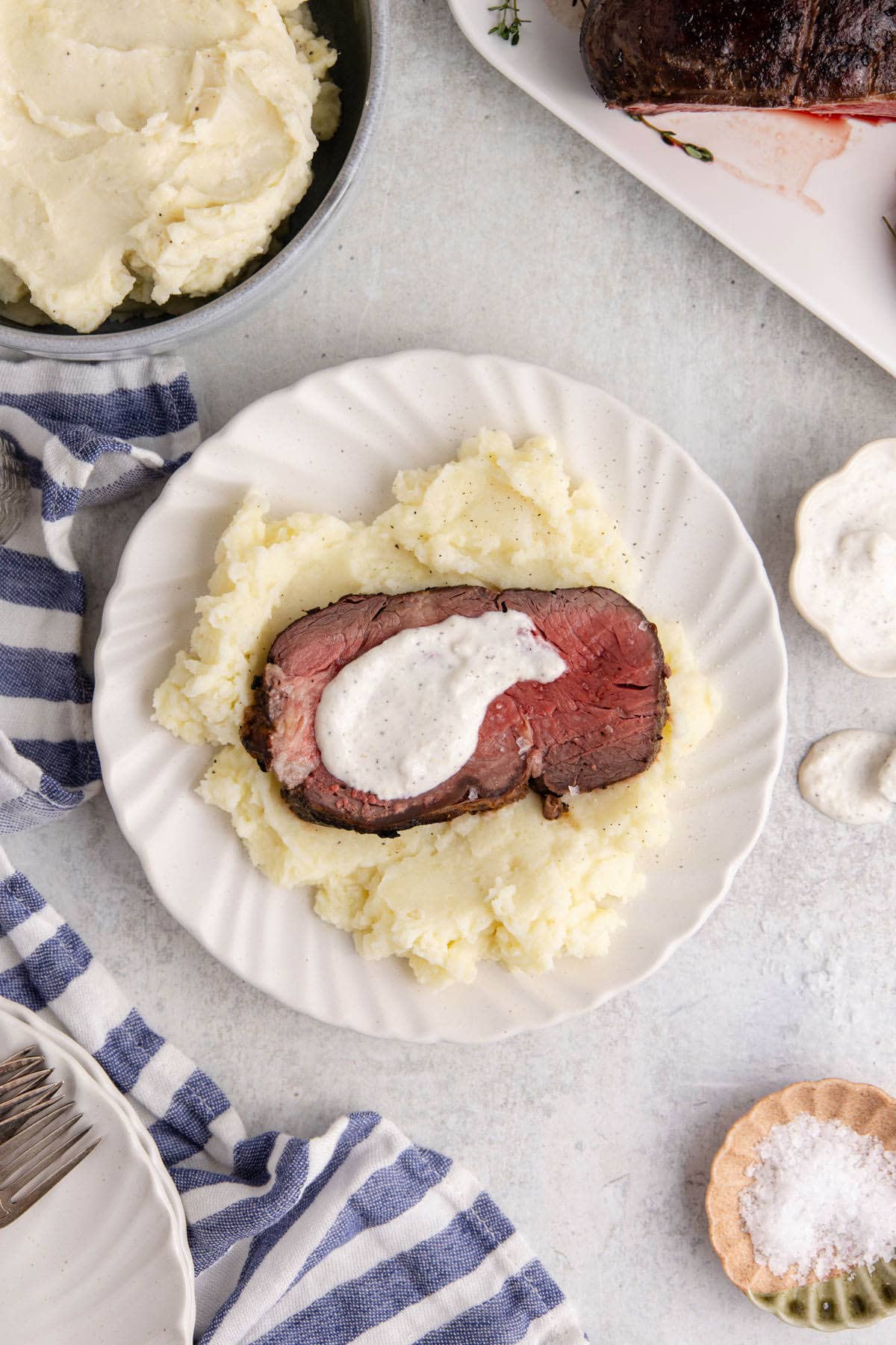 Reverse Sear Beef Tenderloin plated with mashed potatoes and creamy horseradish sauce on top