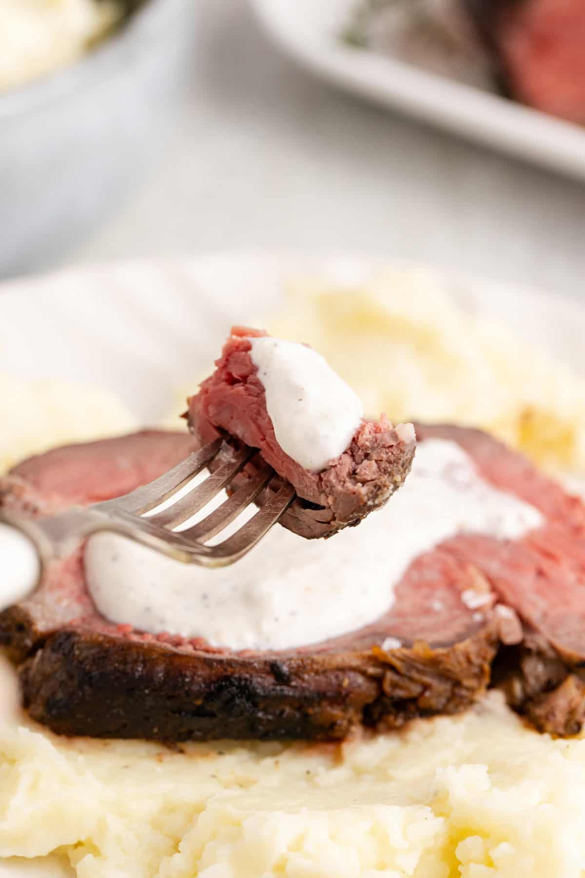 Reverse Sear Beef Tenderloin piece on a fork with creamy sauce