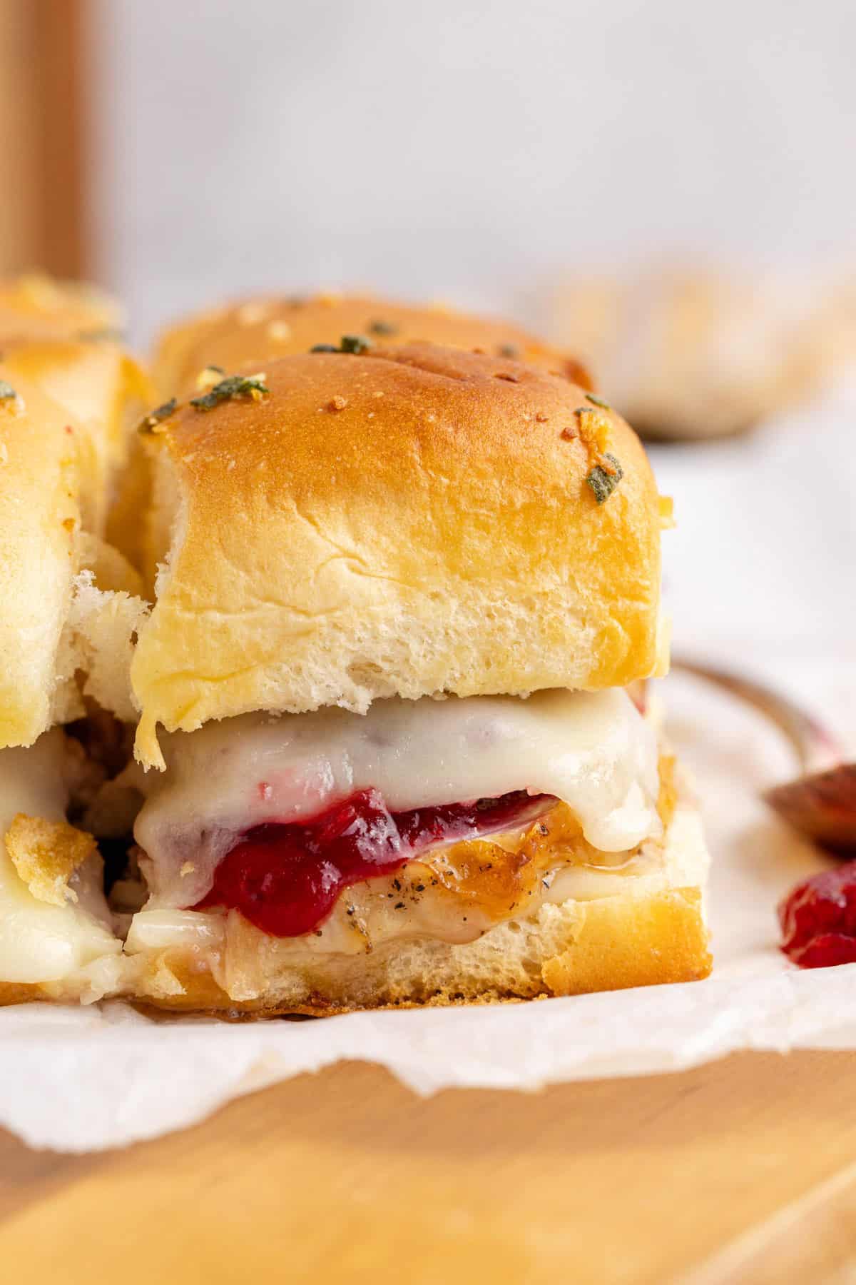 Turkey Sliders Topped with Cheese and Cranberry Sauce on a Cutting Board
