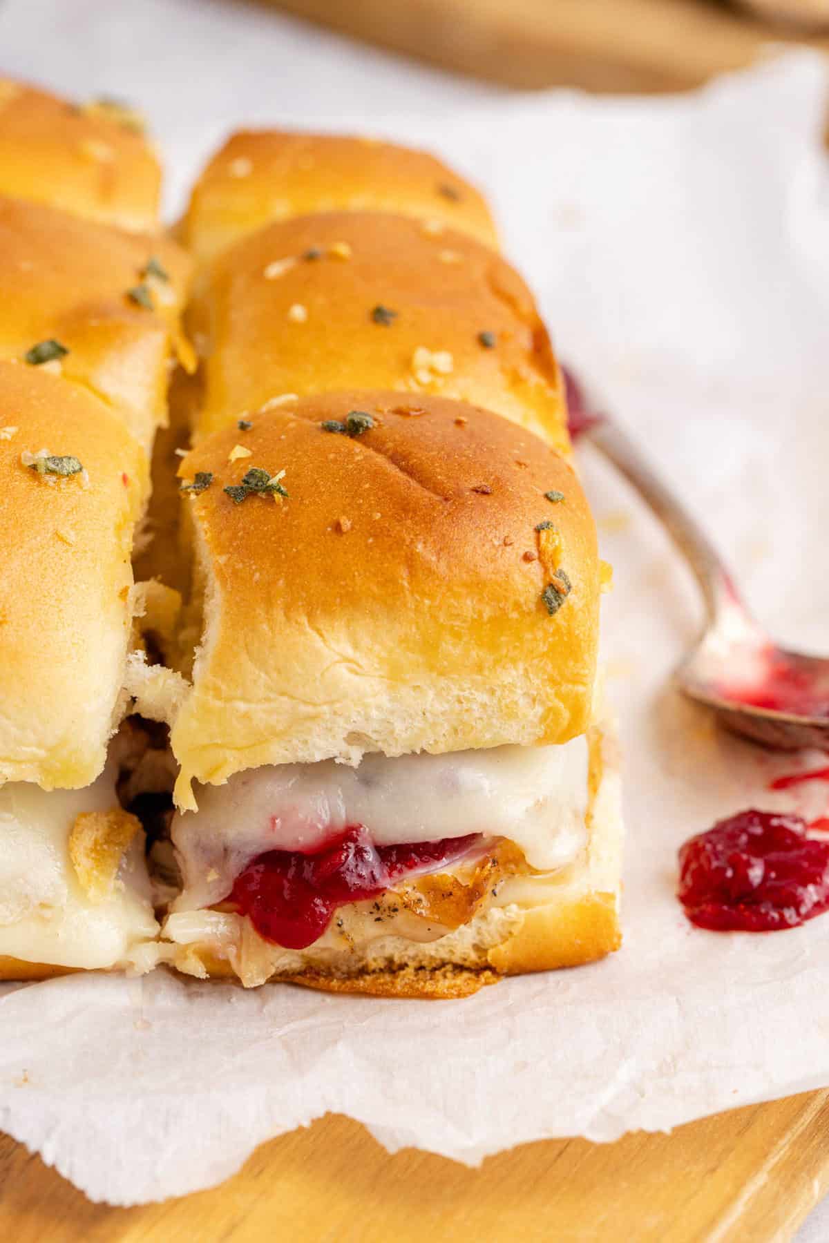 Turkey Sliders Topped with Cheese and Cranberry Sauce on a Cutting Board