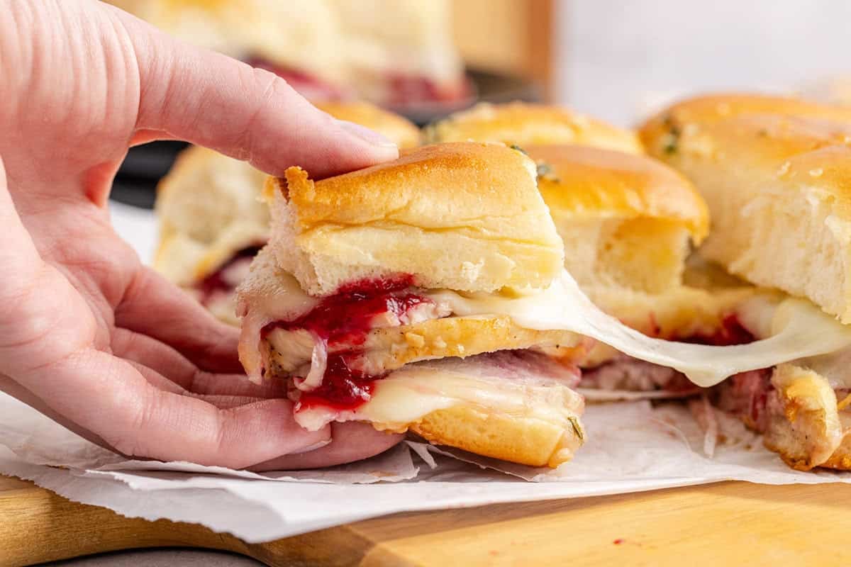 Hand Pulling Turkey Sliders on Hawaiian Rolls with Melted Cheese