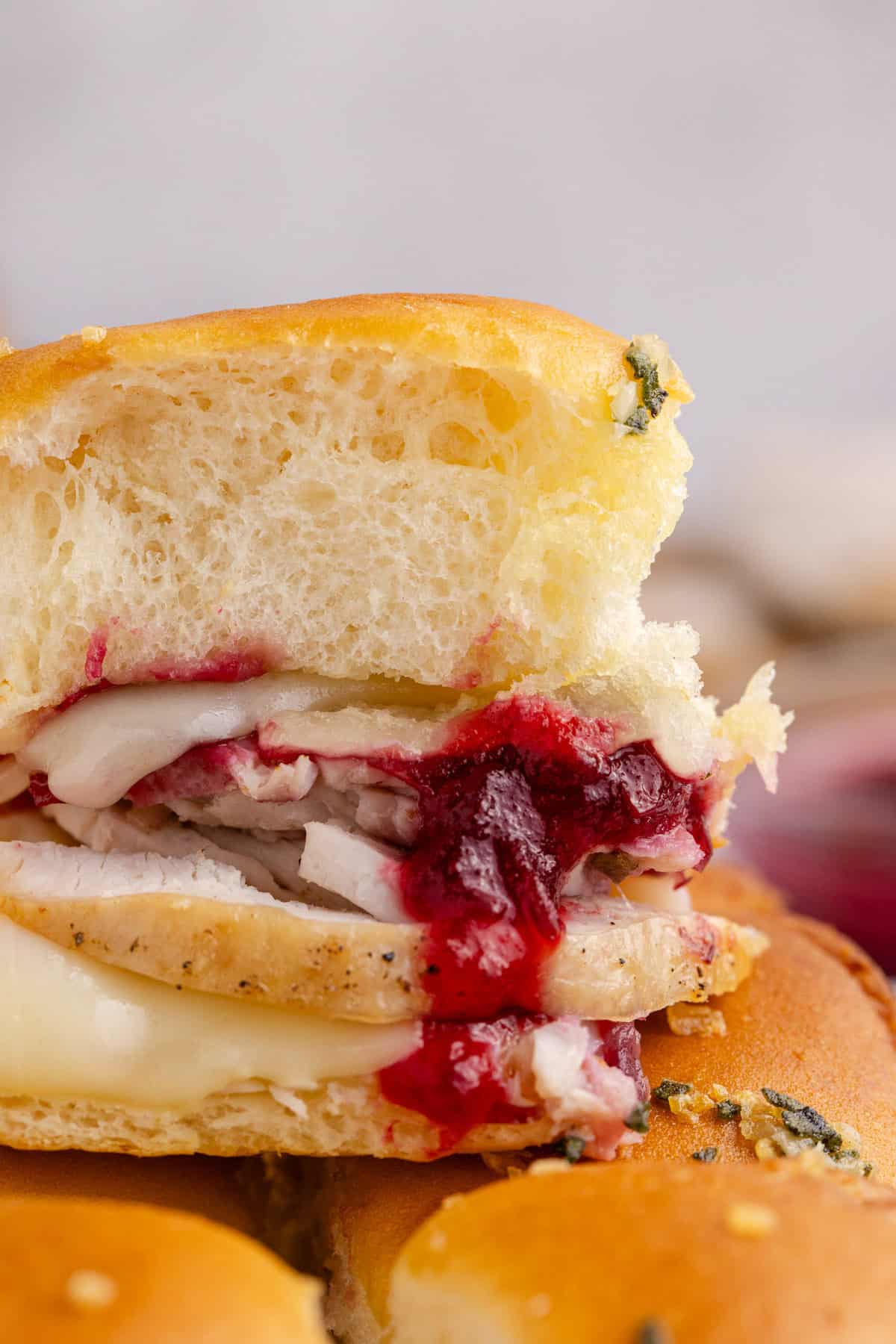 Stacked Turkey Sliders on Hawaiian Rolls Topped with Melted Cheese and Cranberry Sauce