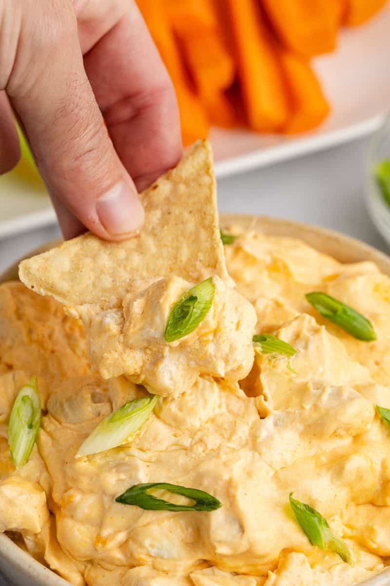 Slow Cooker Buffalo Chicken Wing Dip in a bowl with a chip scoop above it