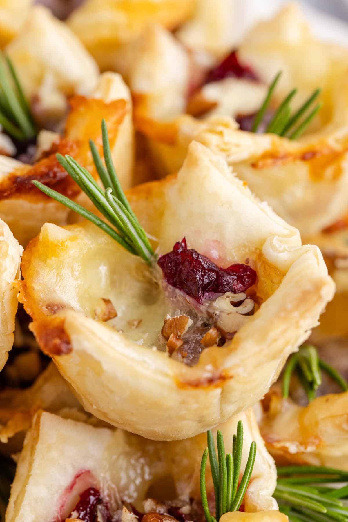 Close Up Cranberry Brie Bites Puff Pastry Stacked and Garnished with Fresh Rosemary