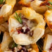 Close Up Cranberry Brie Bites Stacked on a Plate and Garnished with Rosemary Sprigs