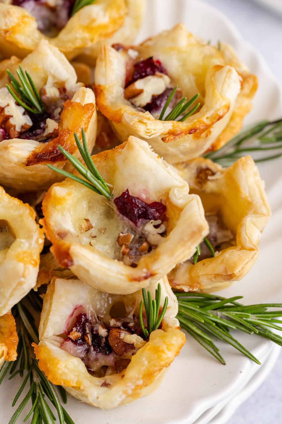 Cranberry Brie Bites Stacked and Served on a Plate and Garnished with Fresh Rosemary Sprigs