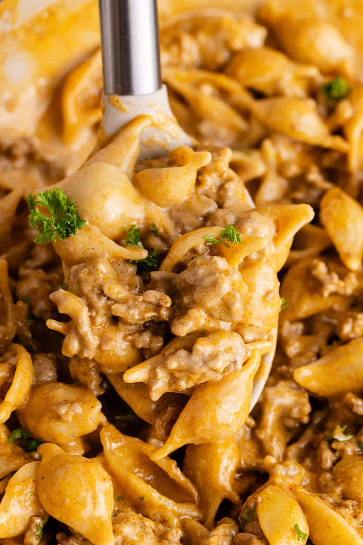 Homemade Hamburger Helper in a skillet with a serving spoon over top up close