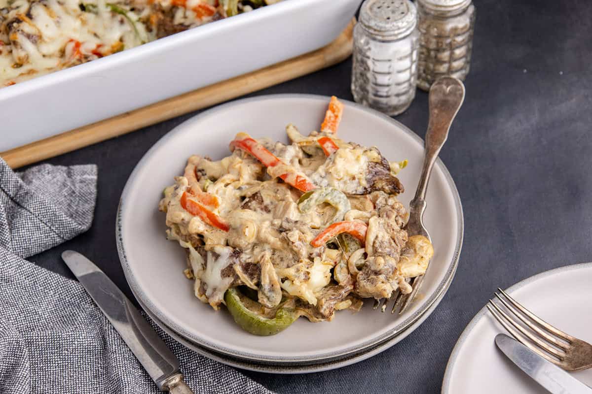 Philly Cheesesteak Casserole on a plate with the baking dish behind