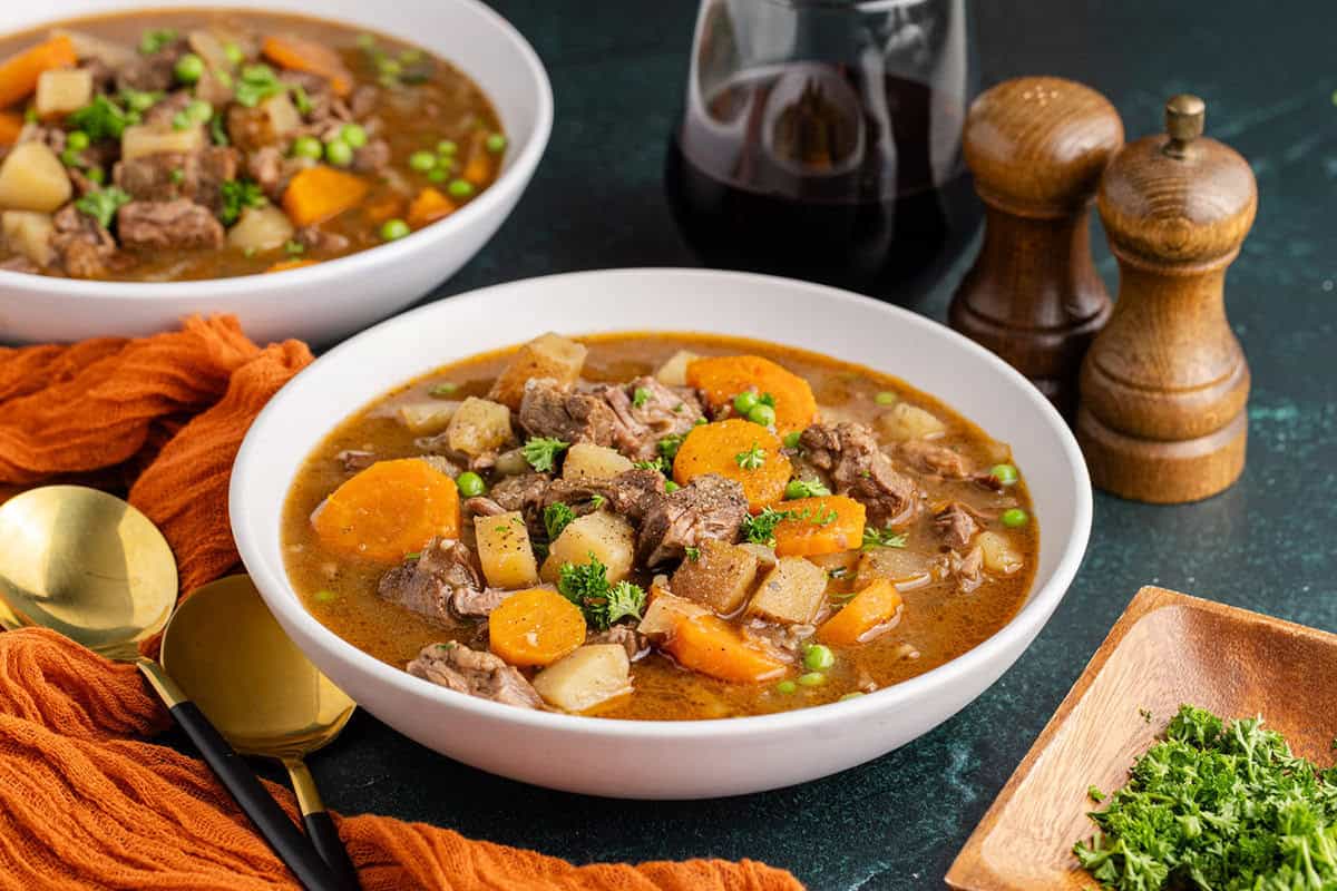 Slow Cooker Beef Stew in a bowl garnished with parsley with another bowl in the back
