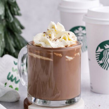 Starbucks Peppermint Hot Chocolate in a mug with take away cups in the back