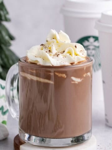 Starbucks Peppermint Hot Chocolate in a mug with take away cups in the back