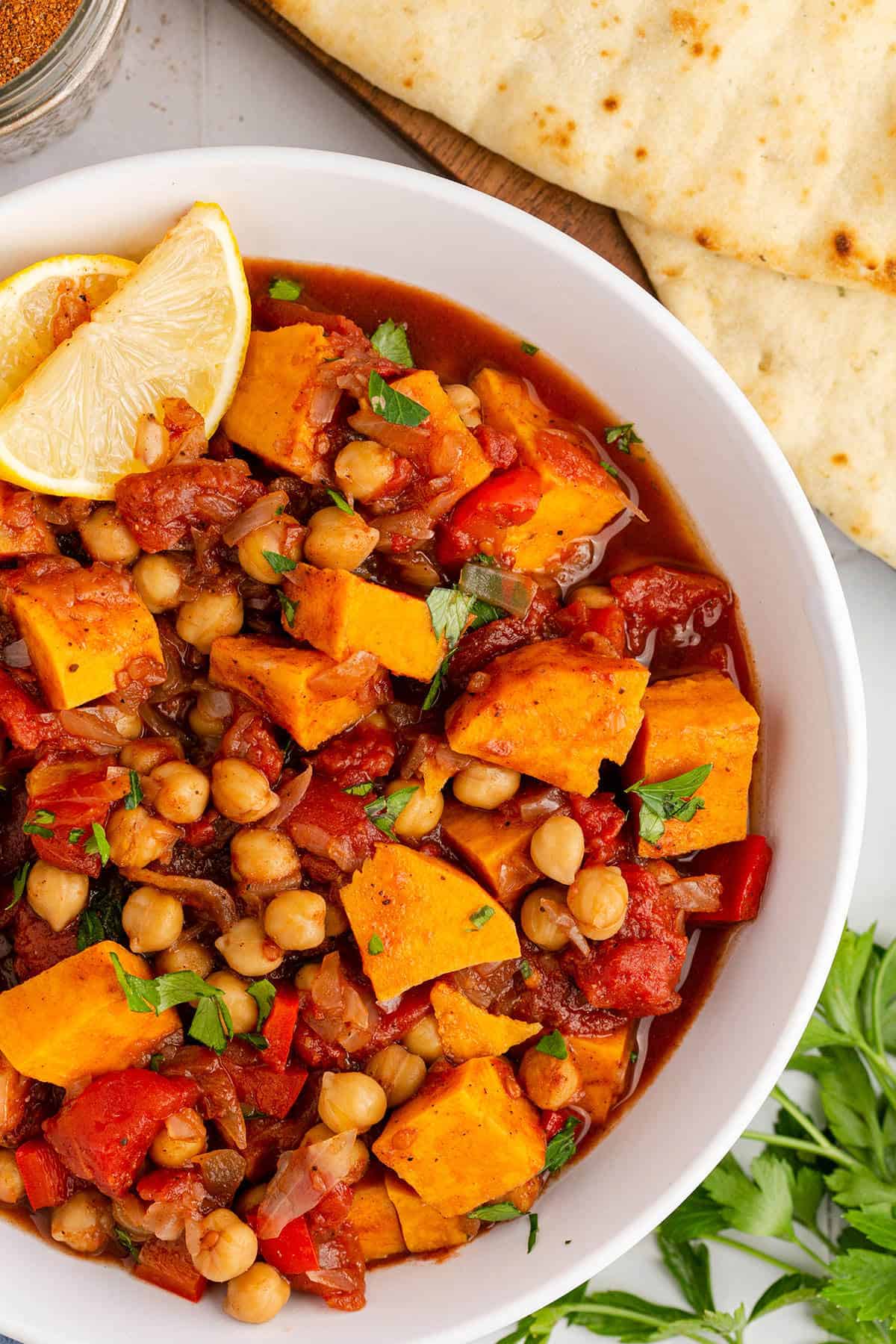 Close Up Sweet Potato Skillet Served in a Bowl and Garnished with Parsley and Lemon Wedge