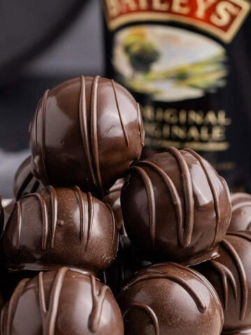 Baileys Truffles on a plate with a bottle of baileys in the back up close