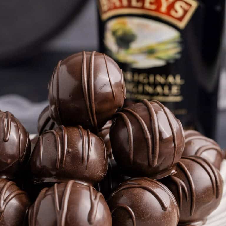 Baileys Truffles on a plate with a bottle of baileys in the back up close