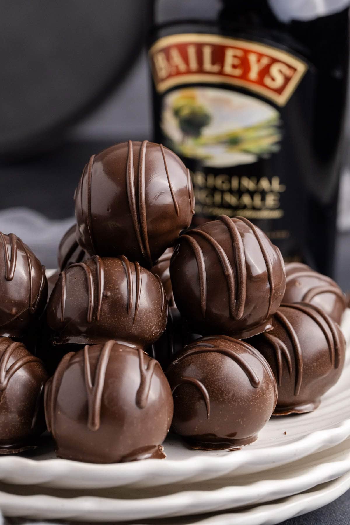 Baileys Truffles on a plate with a bottle of baileys in the back