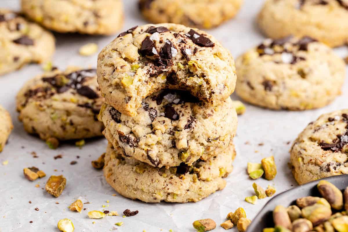 Pistachio Chocolate Chip Cookies stacked with nuts all around