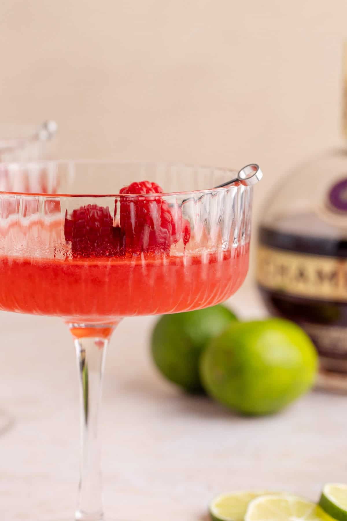 Raspberry Martini on a counter close up with limes in the back