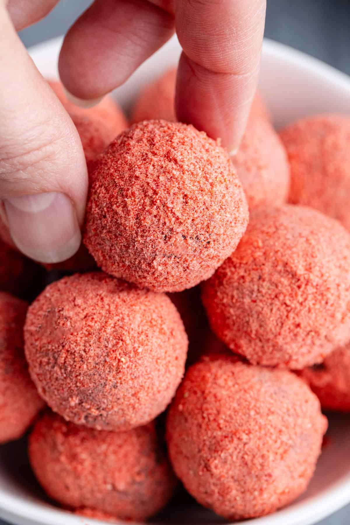 Strawberries Chocolate Truffles in a bowl and one being picked up