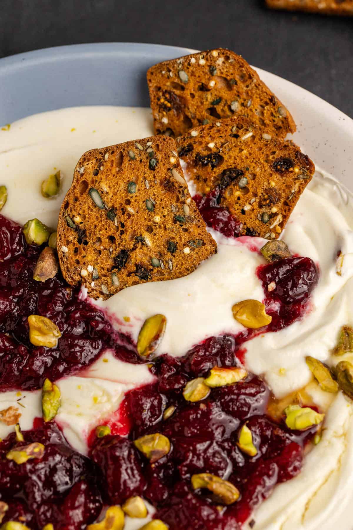 Whipped Goat Cheese close up of crackers in a bowl with cranberry sauce and pistachios