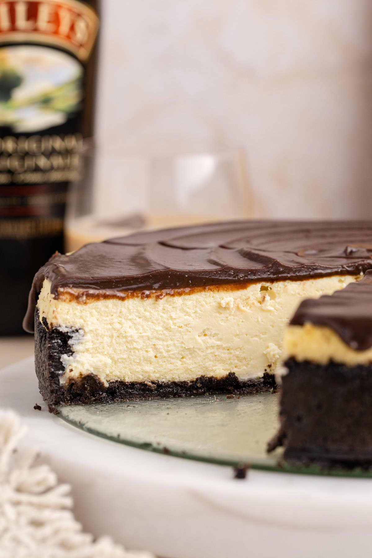 Baileys Cheesecake with a slice taken and a bottle in the back