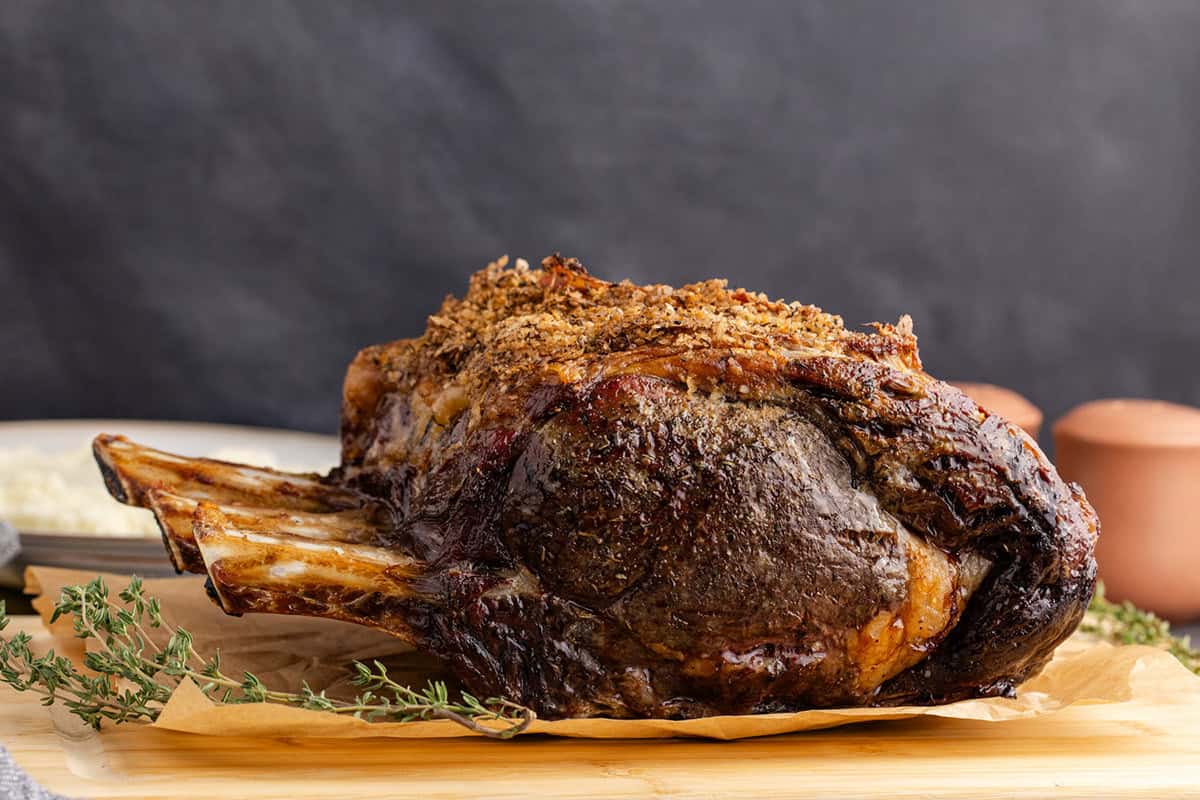 Bone In Prime Rib Roast on a cutting board with fresh thyme