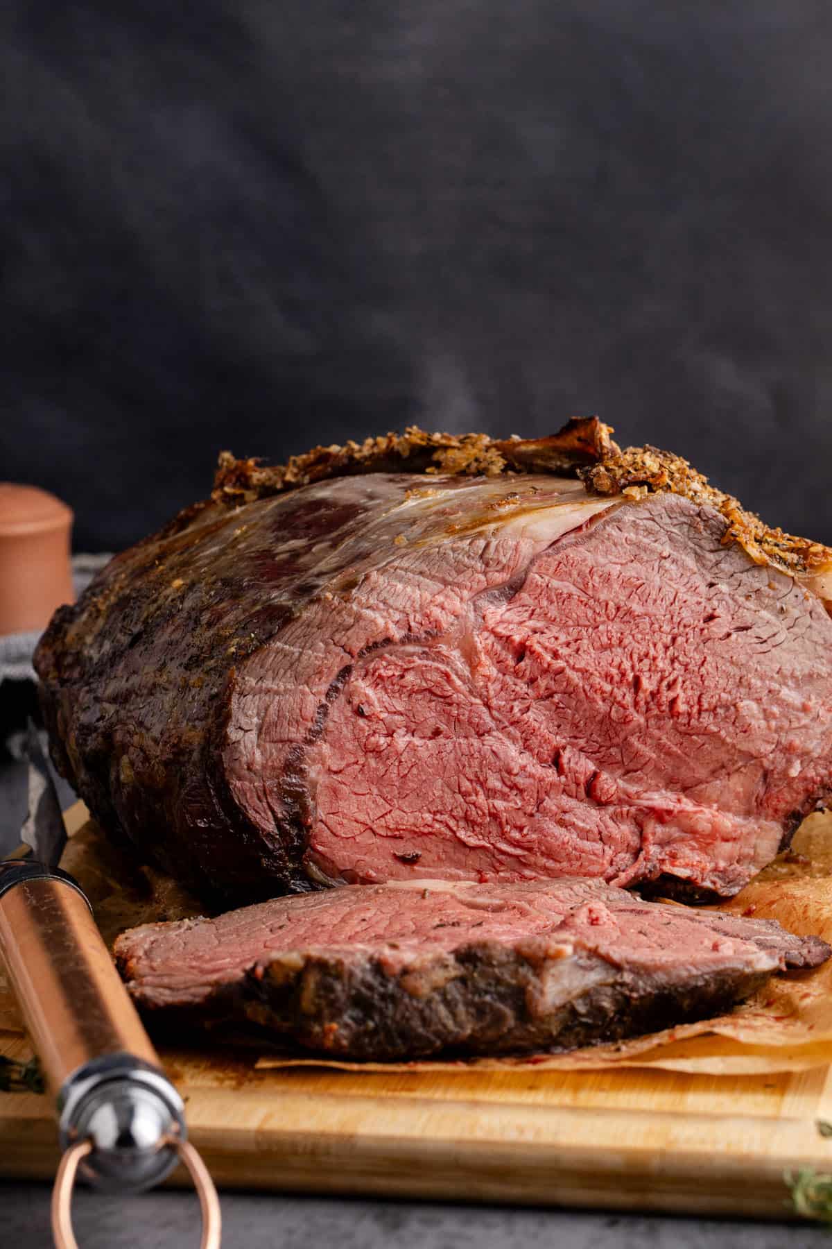 Bone In Prime Rib Roast on a cutting board with a piece sliced in front