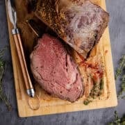 Bone In Prime Rib Roast on a cutting board with a piece sliced from above