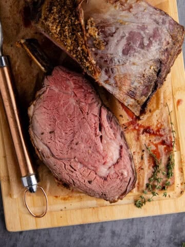 Bone In Prime Rib Roast on a cutting board with a piece sliced from above