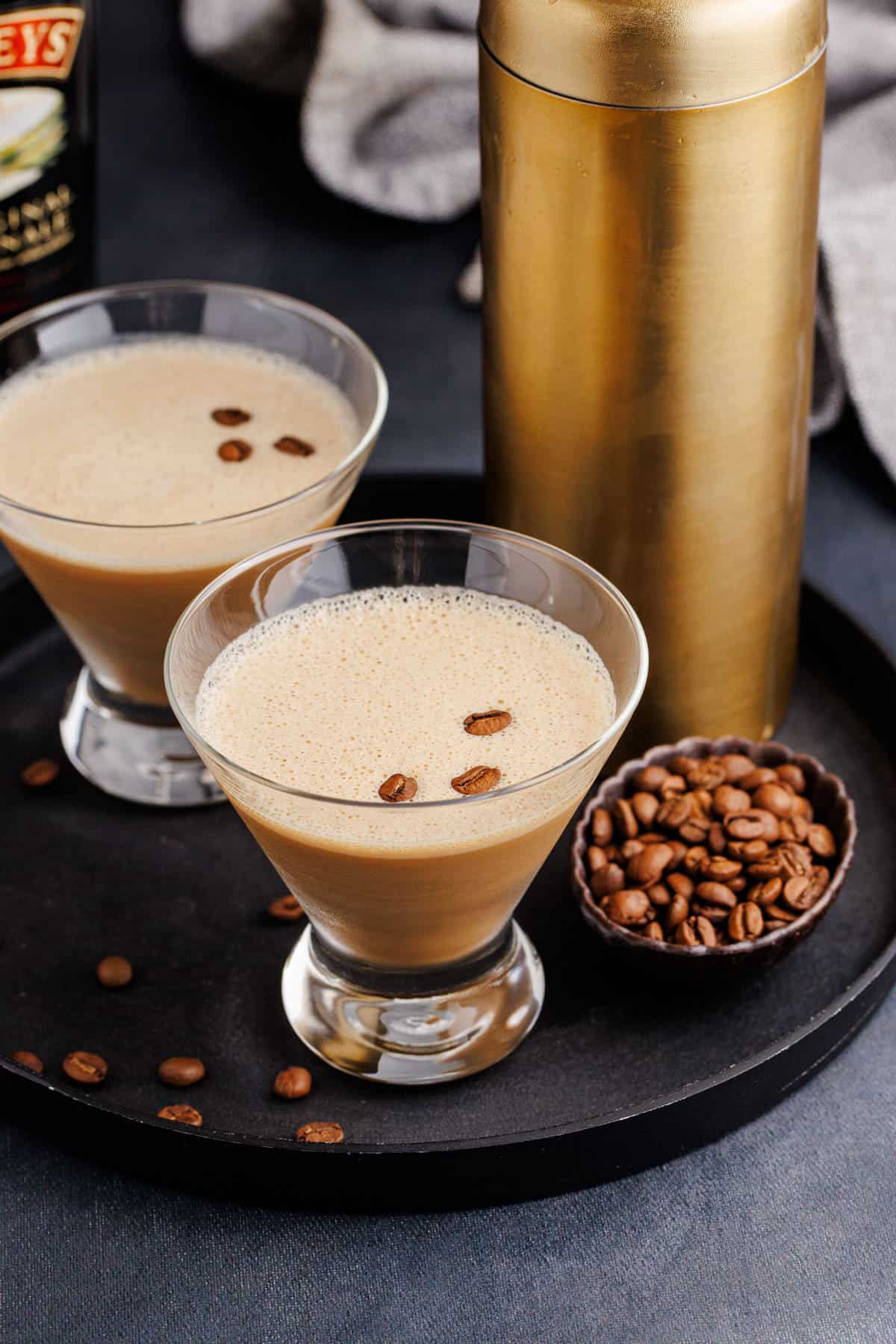 Espresso Martini with Baileys on a Tray Garnished with Coffee Beans and Cocktail Shaker in Background